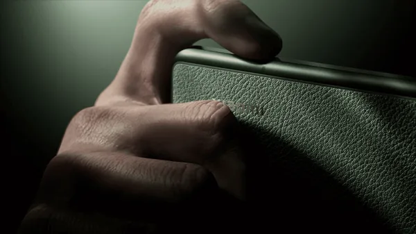 Hand gripping a textured phone back under dramatic studio lighting